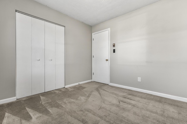 unfurnished bedroom with a closet, a textured ceiling, baseboards, and carpet floors