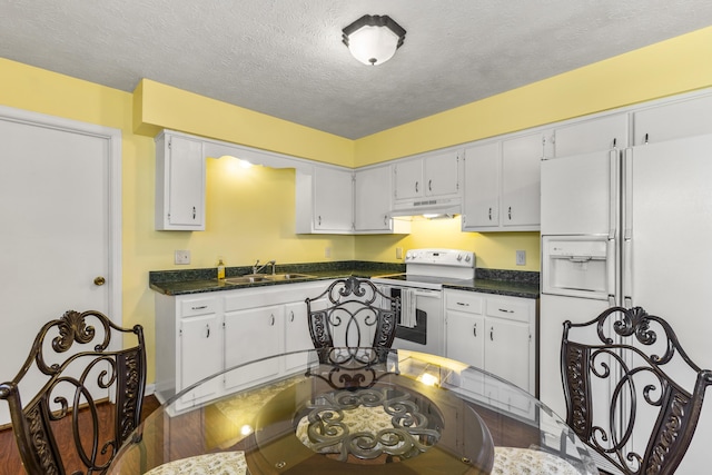 kitchen with under cabinet range hood, a sink, a textured ceiling, white appliances, and white cabinets