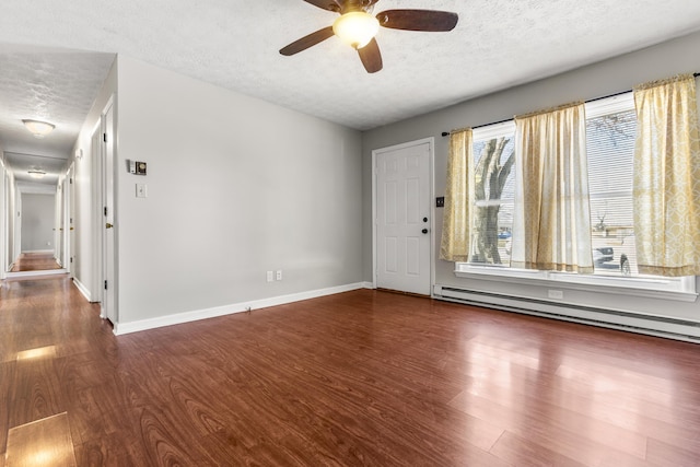 interior space featuring a baseboard heating unit, baseboards, a textured ceiling, and wood finished floors