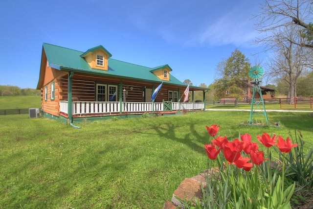 view of front of home featuring central AC unit, covered porch, fence, log siding, and a front yard