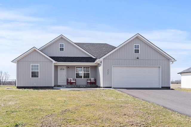 view of front facade with driveway, roof with shingles, an attached garage, a front lawn, and a porch