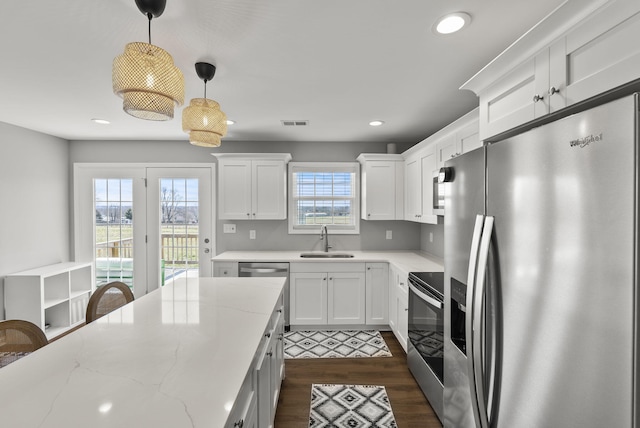 kitchen with dark wood-style floors, visible vents, appliances with stainless steel finishes, white cabinets, and a sink