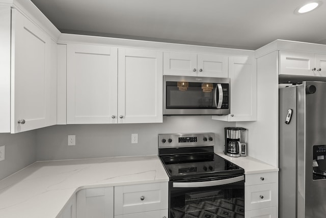 kitchen featuring white cabinetry, appliances with stainless steel finishes, and light stone counters