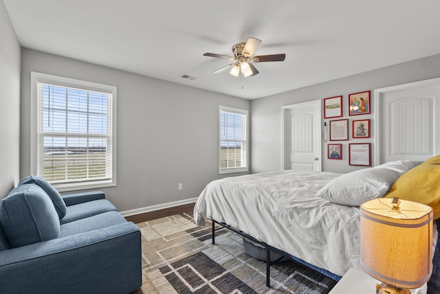 bedroom featuring a ceiling fan, visible vents, baseboards, and wood finished floors