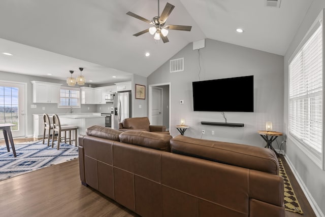 living room featuring baseboards, visible vents, a ceiling fan, dark wood-style flooring, and vaulted ceiling