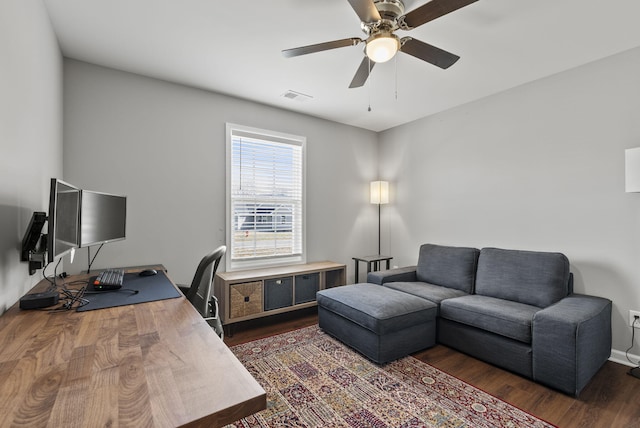 home office with dark wood-style floors, visible vents, and a ceiling fan