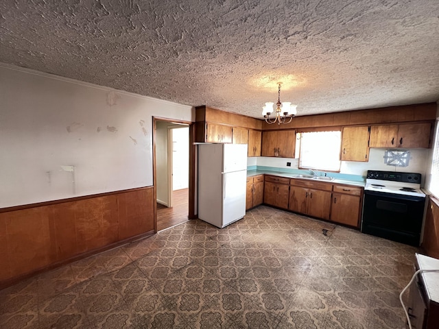 kitchen featuring brown cabinets, a wainscoted wall, electric range oven, freestanding refrigerator, and a chandelier