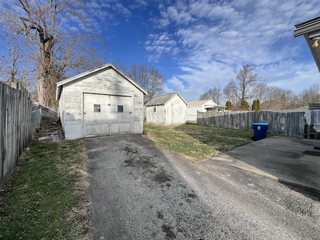 detached garage with aphalt driveway and fence