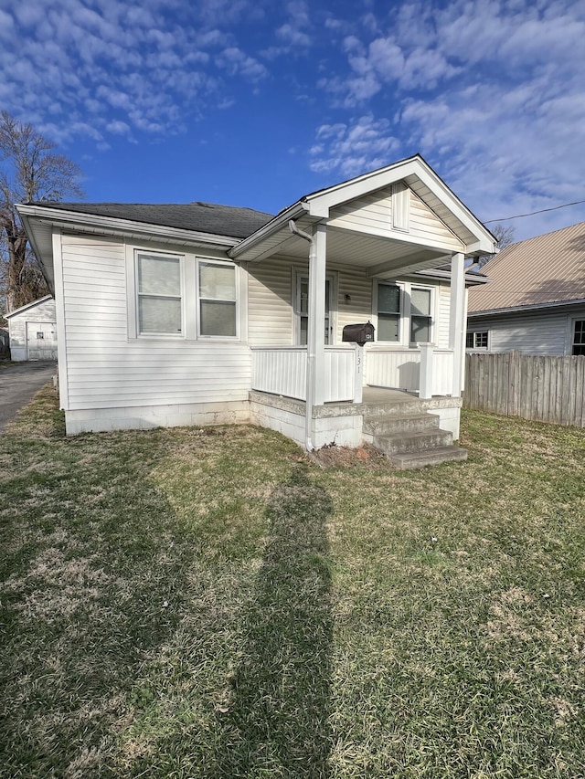 view of front of house with covered porch, a front lawn, and fence