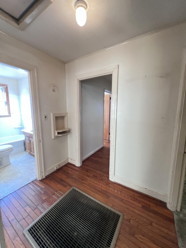 hall featuring hardwood / wood-style flooring, baseboards, and visible vents