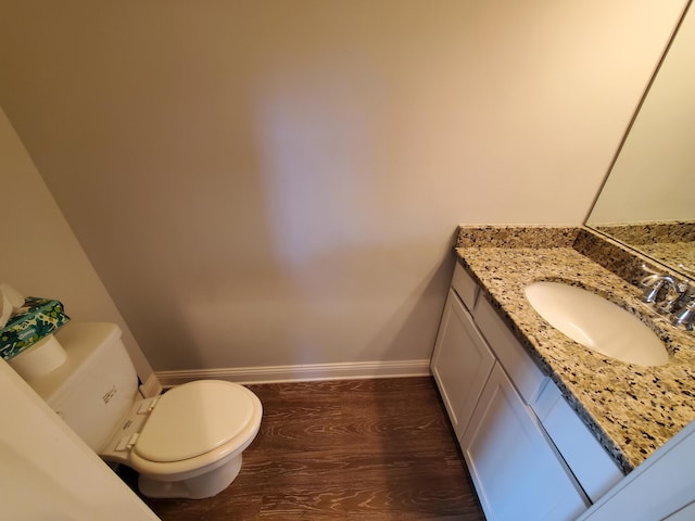 bathroom featuring toilet, baseboards, wood finished floors, and vanity