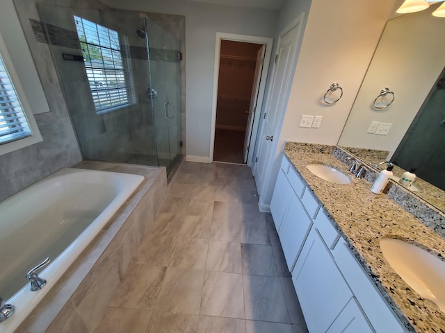 bathroom with a walk in closet, a sink, a bath, and a shower stall