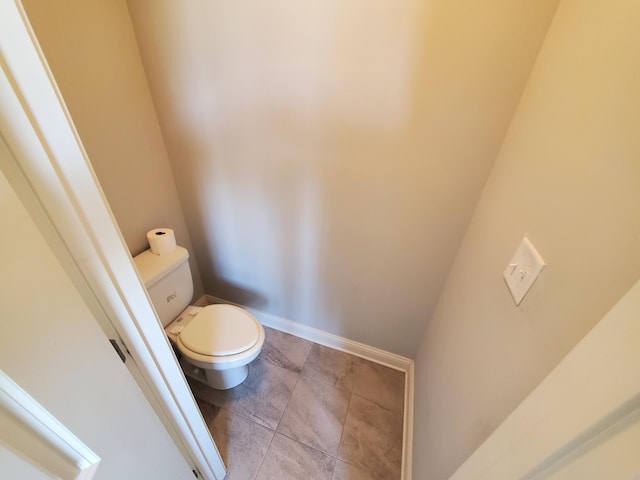 bathroom featuring toilet, baseboards, and tile patterned floors