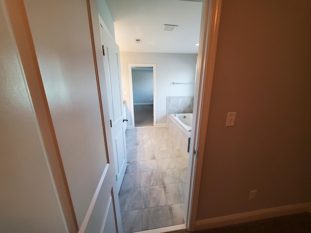 hallway with baseboards, visible vents, and light tile patterned flooring