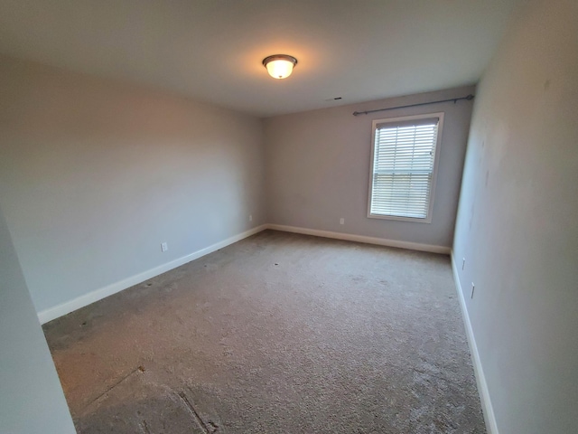 empty room featuring carpet floors and baseboards