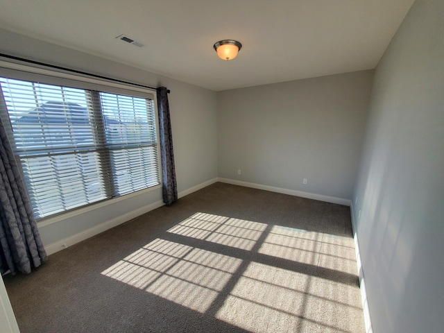 spare room with carpet, visible vents, and baseboards