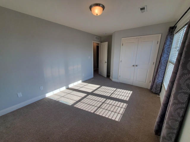 unfurnished bedroom with carpet, visible vents, and baseboards