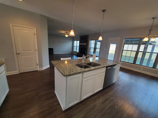 kitchen with dark wood-style flooring, stainless steel dishwasher, open floor plan, a kitchen island with sink, and a sink