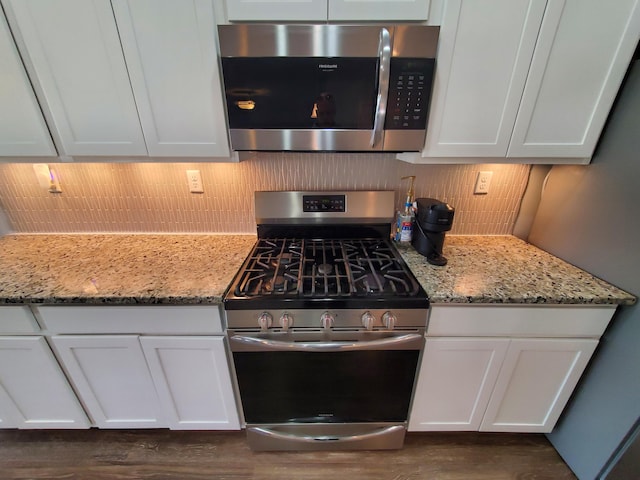 kitchen with appliances with stainless steel finishes, light stone countertops, white cabinetry, and tasteful backsplash