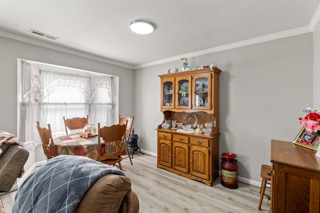 dining room featuring baseboards, ornamental molding, visible vents, and light wood-style floors