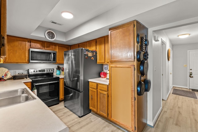 kitchen with light wood finished floors, light countertops, appliances with stainless steel finishes, and visible vents