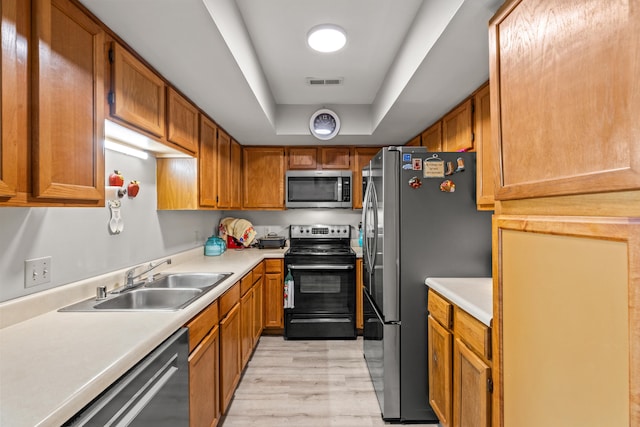 kitchen featuring visible vents, appliances with stainless steel finishes, a tray ceiling, light countertops, and a sink