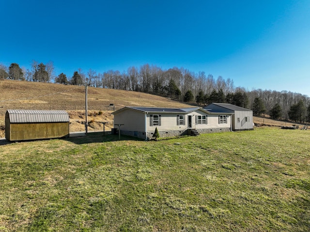 back of property featuring an outbuilding, a yard, entry steps, crawl space, and a rural view