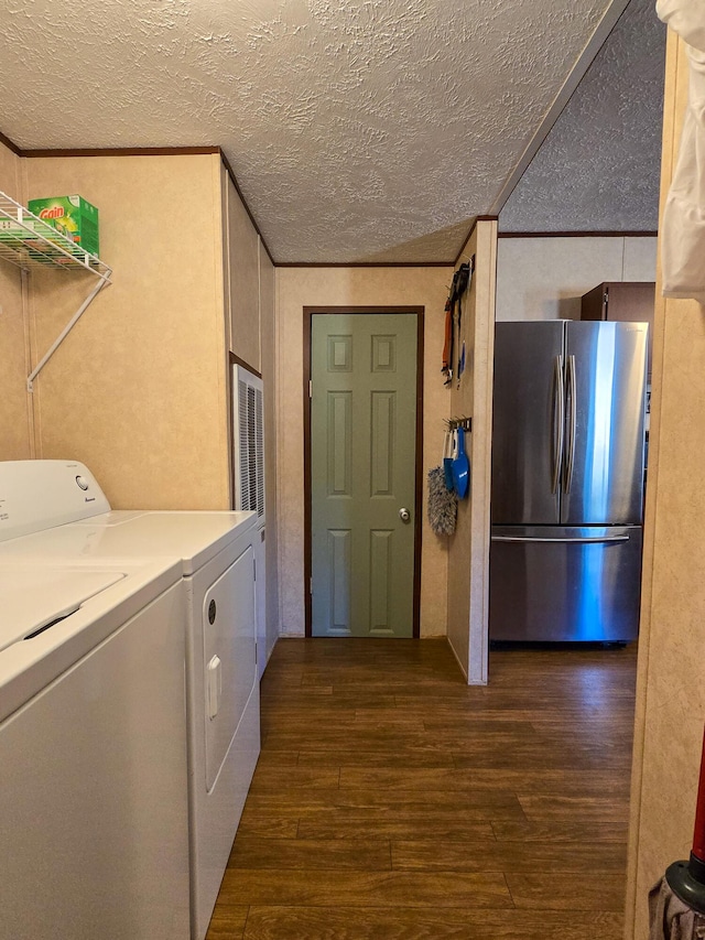 washroom featuring a textured ceiling, laundry area, dark wood finished floors, ornamental molding, and washing machine and clothes dryer