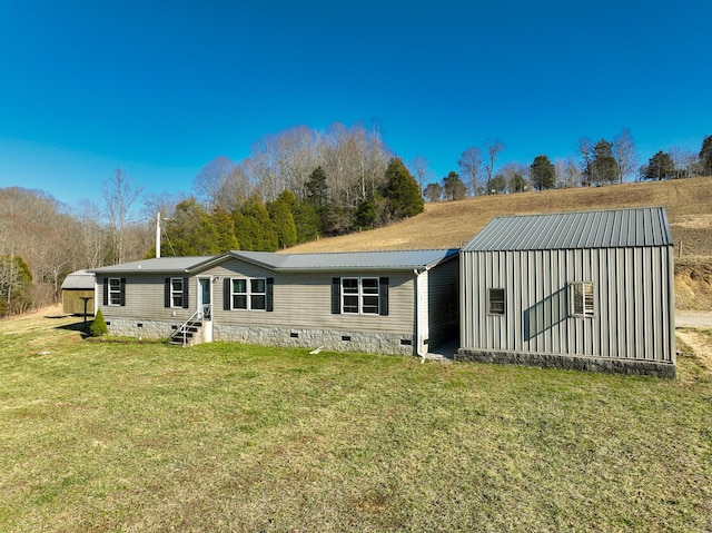 back of property featuring entry steps, crawl space, a lawn, and metal roof