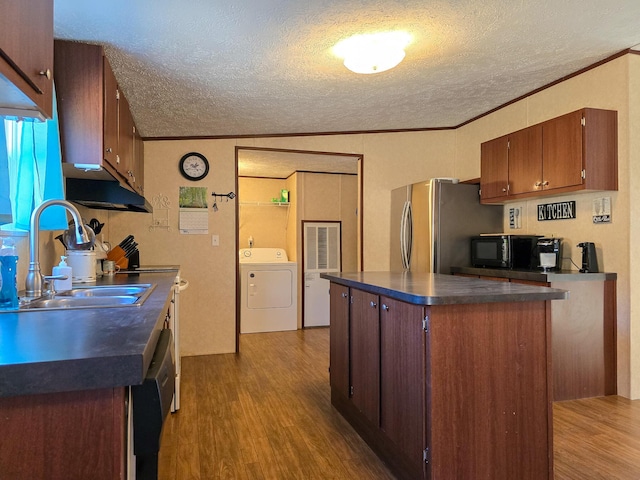 kitchen with wood finished floors, dark countertops, a sink, and freestanding refrigerator