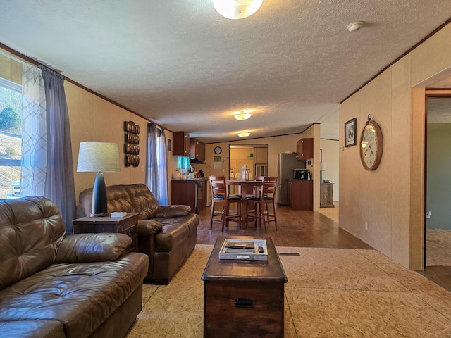 living room featuring ornamental molding, light wood-style flooring, and a textured ceiling