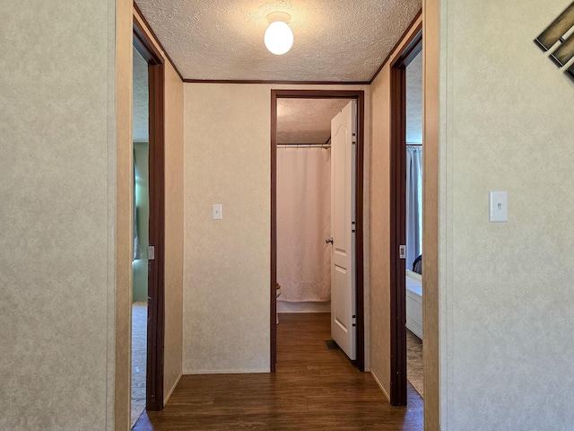 hallway featuring a textured wall, a textured ceiling, and wood finished floors