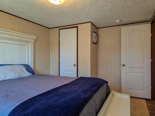 bedroom with a textured ceiling, ornamental molding, and wood finished floors