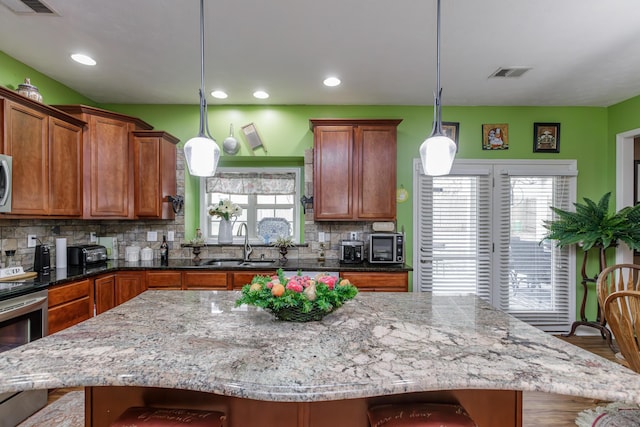 kitchen with tasteful backsplash, visible vents, stainless steel electric range oven, brown cabinets, and a sink