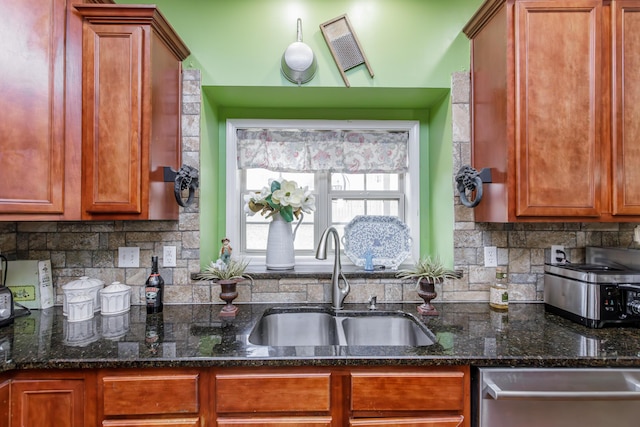 kitchen with stainless steel dishwasher, tasteful backsplash, dark stone counters, and a sink