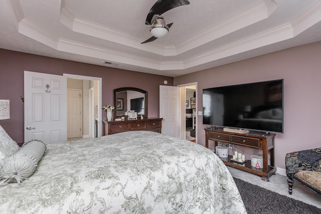 carpeted bedroom featuring visible vents, a tray ceiling, a ceiling fan, and ornamental molding