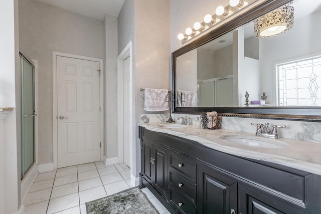 full bathroom featuring double vanity, a stall shower, tile patterned flooring, and a sink