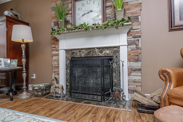 room details featuring a fireplace with raised hearth and wood finished floors