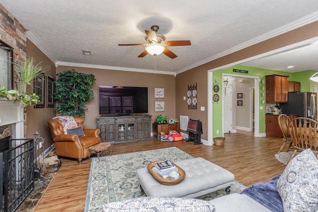 living room featuring light wood-style floors, a fireplace, and ornamental molding