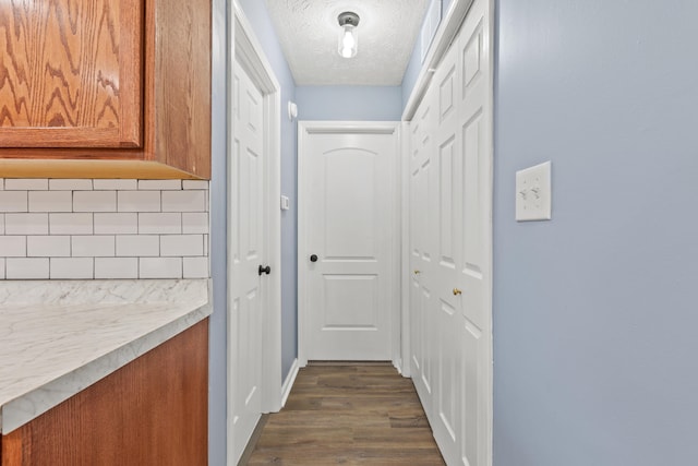 corridor with a textured ceiling and dark wood-type flooring