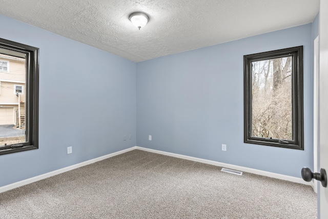 unfurnished room featuring carpet, a textured ceiling, visible vents, and baseboards