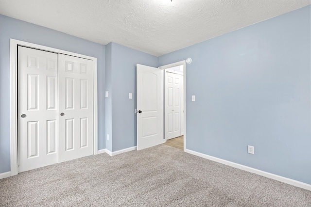 unfurnished bedroom with a textured ceiling, a closet, carpet flooring, and baseboards