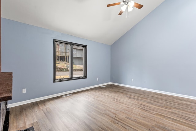 interior space with vaulted ceiling, wood finished floors, visible vents, and baseboards