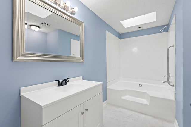 bathroom featuring a skylight, visible vents, marble finish floor, a textured ceiling, and vanity