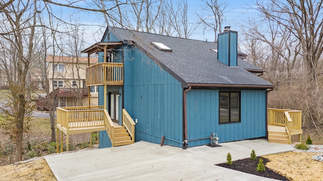 view of front of home featuring a balcony, a shingled roof, a chimney, and a patio