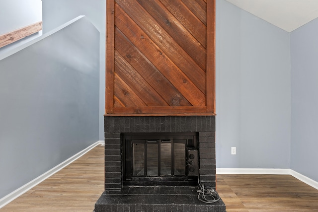 room details with a fireplace, baseboards, and wood finished floors