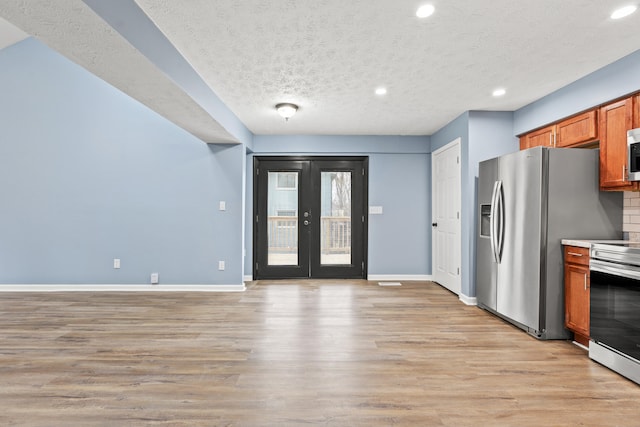 kitchen featuring baseboards, brown cabinetry, appliances with stainless steel finishes, french doors, and light wood-style floors