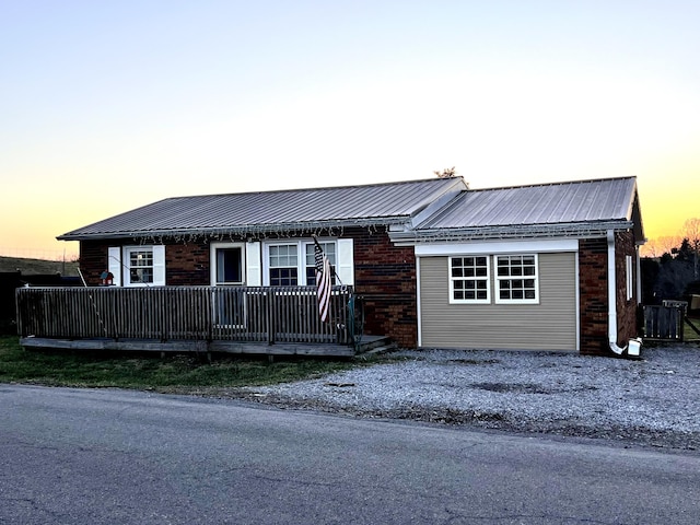 ranch-style house featuring metal roof and brick siding