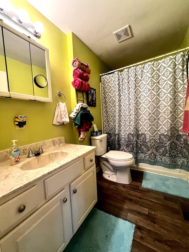 bathroom with toilet, a shower with shower curtain, wood finished floors, vanity, and visible vents