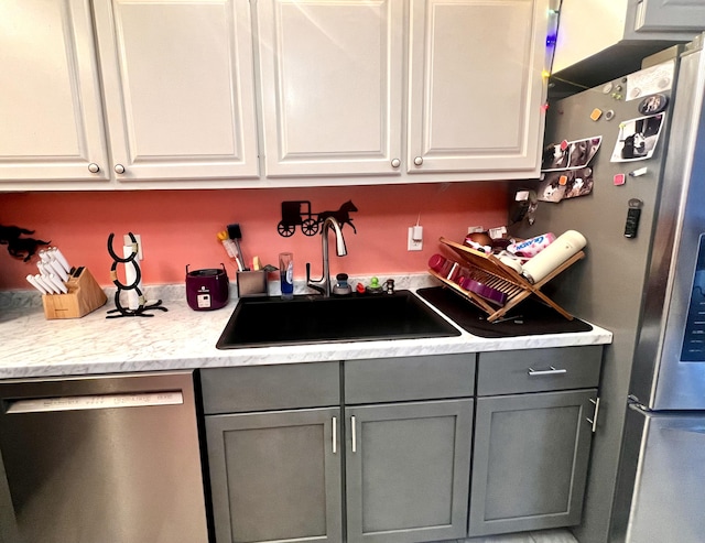 kitchen with white cabinetry, appliances with stainless steel finishes, gray cabinets, and a sink